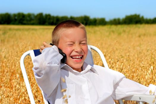 Cheerful Boy Laughing and calling on mobile phone in the wheat field