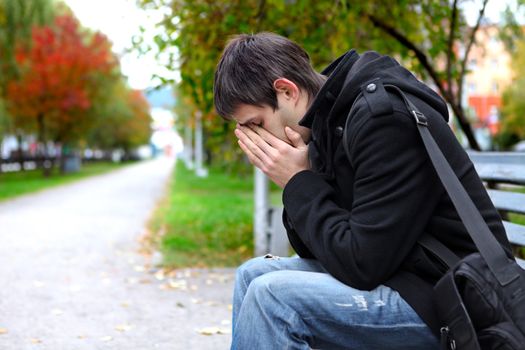 Sad young man sitting on the bench outdoor