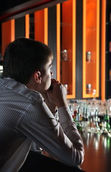 Sad and Lonely Young Man Sitting in the Darkness at the Bar counter