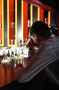 Sad and Lonely Young Man Sitting in the Darkness at the Bar counter