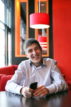 Happy Young Man with Mobile Phone at the Home