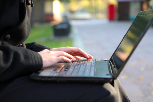 Person working on Laptop at the Autumn Park. Hands Closeup