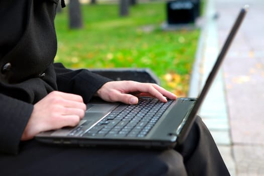 Person working on Laptop at the Autumn Park. Hands Closeup