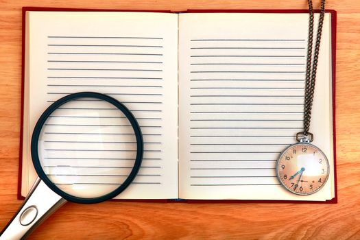 Writing Pad with Loupe and Old Watch on the Wooden Background