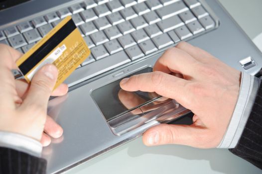 man's hand entering data using notebook while holding a credit card in the other hand 