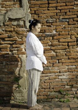 Buddhist woman standing meditating against ancient temple