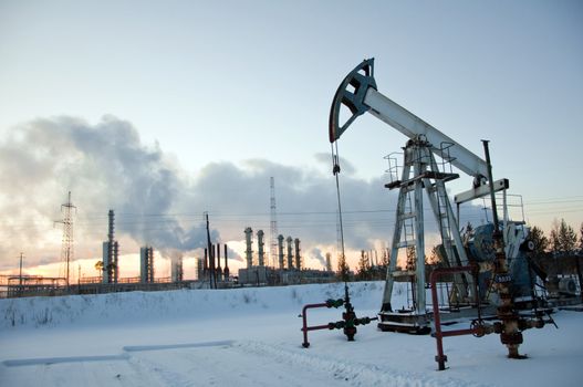 oil pump on  background of  industrial landscape and winter sky in  smoke