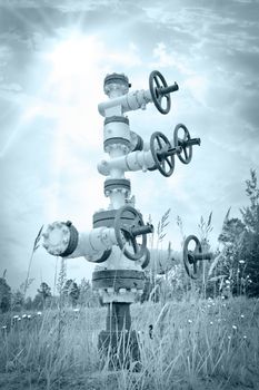 Oil, gas industry. Wellhead with valve armature on a sky background. Toned.