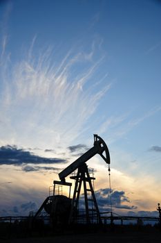 Oil and gas industry. Silhouette oil pump on a sunset sky background.