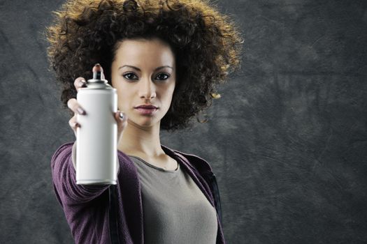 Beautiful girl about to draw a graffiti on a wall with copyspace