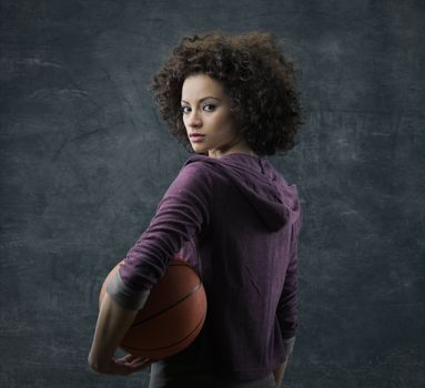 Portrait of young beautiful woman holding a basketball