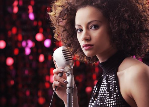 Young female singer with brown curly hair singing a song 