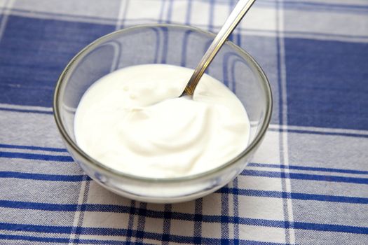 Yoghurt in a bowl with spoon on table