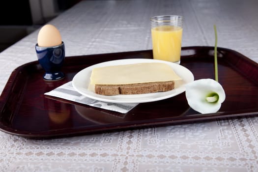 Breakfast on plate with bread, cheese, egg and orange jus