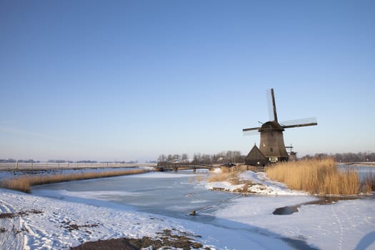 Windmill in winter time with snow and blue sky