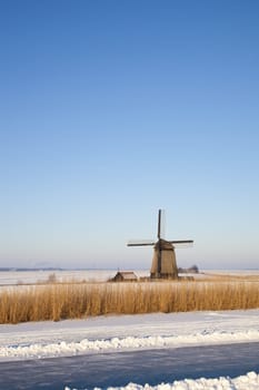 Windmill in winter time with snow,ice and blue sky