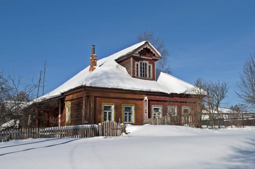 Old wooden house in snow, winter sunny day