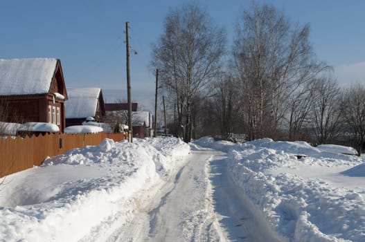 Road among the snowdrifts in Russian village