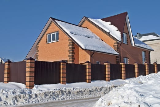 New cottage of red brick, covered with snow, sunny winter day