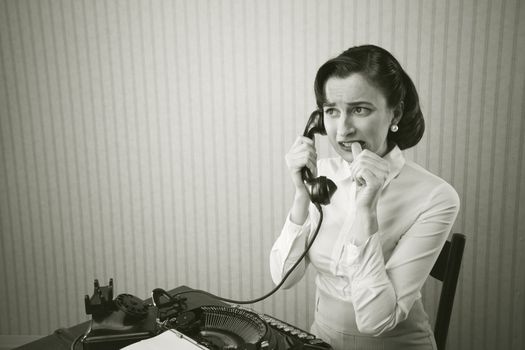 Woman embarrassed talking on phone at her desk