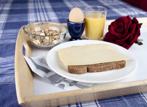 Breakfast on plate with bread, cheese, egg, cruesli and orange jus