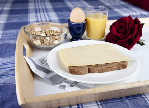 Breakfast on plate with bread, cheese, egg, cruesli and orange jus