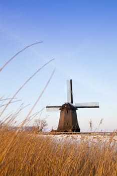 Windmill in winter time with snow and blue sky