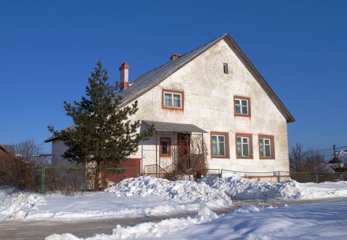 Old white stone cottage in a sunny winter day