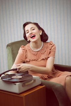 Smiling woman listening to music from a turntable