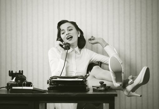 Business woman puts her feet up on her desk on the phone 