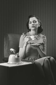 Beautiful woman sitting at armchair, drinking tea 