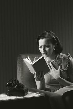 Woman sitting on armchair, reading a horror novel