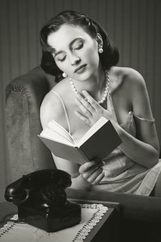 Sensual woman wearing lingerie reading a book on armchair
