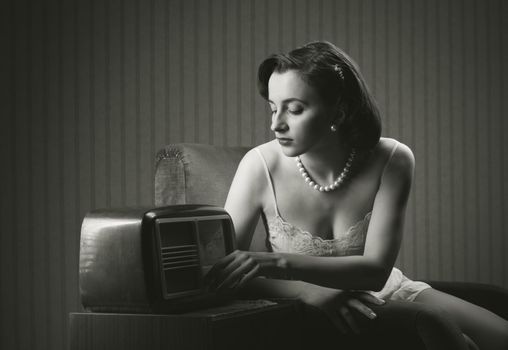 Sensual woman wearing lingerie listening music on old radio