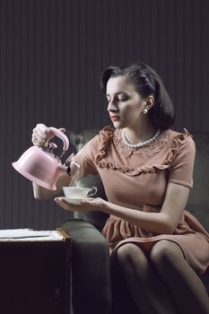 Beautiful woman sitting at armchair, drinking tea 