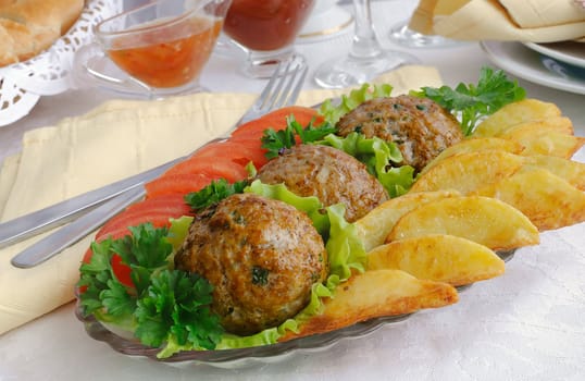 Meatballs with greens on salad leaves with potatoes and tomatoes