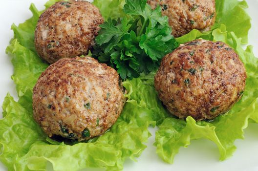 A meatball with greens on salad leaves closeup