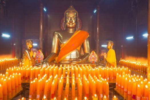 Buddha statuettes with candles in temple