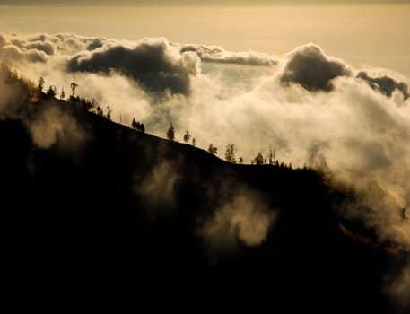 view of the mountains rise above the clouds at sunset