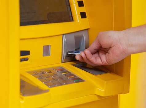 man inserts a plastic card into the ATM