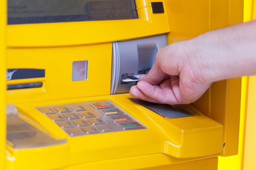 man inserts a plastic card into the ATM