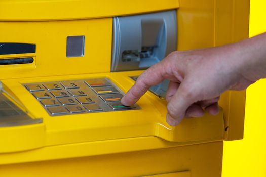 man enters a PIN code in the ATM