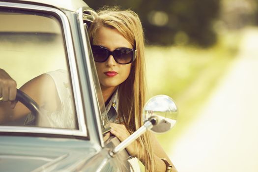 Young woman driving vintage car.