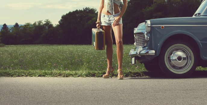 Young sexy girl with suitcase and vintage cars