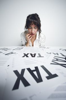 Astonished businesswoman looking at a bunch of worrying tax forms on her desk