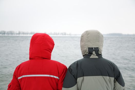 two people in jacket with hood on the river background