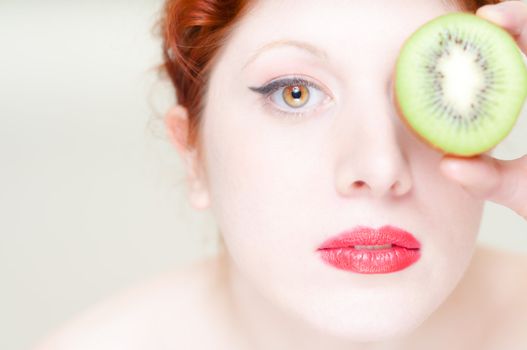 beautiful red hair and lips girl with kiwi on white background