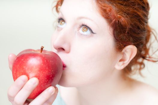 beautiful red hair and lips girl kissing apple on white background