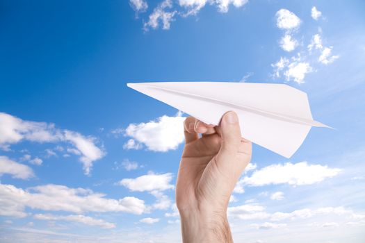 hand with paper airplane on blue sky background