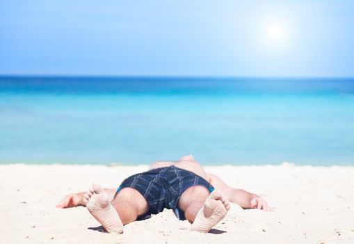 man lies on a  beach on an ocean coast